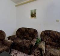 Wohnzimmer in einem Einfamilienhaus mit Stühlen, Bildern und einem Teppich auf dem Boden.