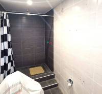 Ein Badezimmer in einem Einfamilienhaus mit schwarz-weißen Fliesen und einer Duschkabine.