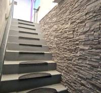 Treppe mit Steinverkleidung in einem Einfamilienhaus, ergänzt durch Scheinwerfer und Teppiche.