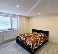 Ein Schlafzimmer in einem Einfamilienhaus mit einem Bett, Holzboden und einfacher Dekoration.