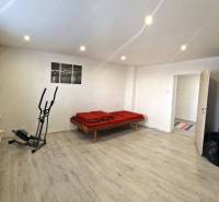 Zimmer in einem Einfamilienhaus, Bett, Ellipsentrainer, Vase, Fenster mit Jalousien, Bild.