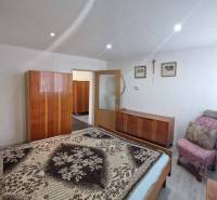 Ein Schlafzimmer in einem Einfamilienhaus mit einem Bett, einem Schrank, einem Sessel und Dekorationen an den Wänden.