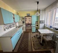 Küche in einer 3-Zimmer-Wohnung mit blauen Schränken und Esstisch.