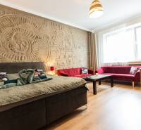 Ein Zimmer in einer 2-Zimmer-Wohnung mit einem Bett, roten Sofas und einem dekorativen Relief an der Wand.