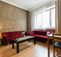 Wohnzimmer in einer Zweizimmerwohnung mit gemusterter Wand und roten Sofas.