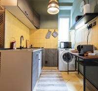 Küche in einer 2-Zimmer-Wohnung mit Kochfeld, Waschmaschine und Kaffeemaschine.