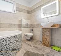 Ein Badezimmer in einem Einfamilienhaus mit stilvollen Keramikfliesen, einer Badewanne und einem Designer-Waschbecken.