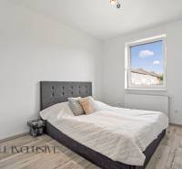 Schlafzimmer im Einfamilienhaus mit einfachem Bett und Fenster, helle Holzböden.