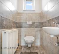 Badezimmer im Einfamilienhaus mit WC, Waschbecken und Heizkörper; helle Fliesen.