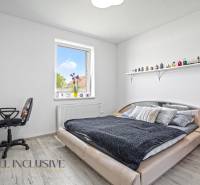 Ein Schlafzimmer in einem Einfamilienhaus mit einem Bett, einem Stuhl, einem Tisch und einem Regal an der Wand.