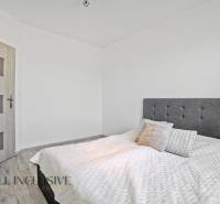 Schlafzimmer im Einfamilienhaus mit gepolstertem Kopfteil und Holztüren.