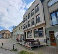 Das Gebäude in der Mostová-Straße in Ružomberok mit Terrasse und umliegenden historischen Bauwerken.