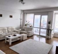 Helles Wohnzimmer mit weißen Sofas in einer 4-Zimmer-Wohnung, Glastüren zur Terrasse.