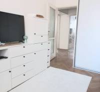 Weißes Wohnzimmer in einer 4-Zimmer-Wohnung mit Fernseher, Schränken und Holzboden.