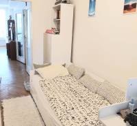 Ein Zimmer in einer 4-Zimmer-Wohnung mit einem Bett, einem Regal und einem Zugang zum Balkon.
