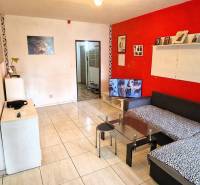 Wohnzimmer mit ausziehbarem Sofa und Fernseher, angrenzend an die Küche in einer 3-Zimmer-Wohnung.