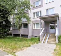 Ein Wohngebäude umgeben von Grün mit einem Zugangspfad in Košice IV, in der Nähe einer 3-Zimmer-Wohnung.