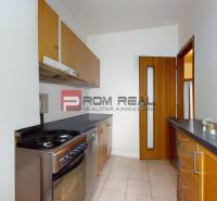 Küche in einer 3-Zimmer-Wohnung mit hellem Fliesenboden und Holzschränken.