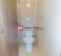 Toilette in einer 3-Zimmer-Wohnung mit hellen Fliesen und Holztüren.