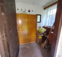 Das Innere der Hütte mit einem Holzschrank und einem Fenster, neben Pappkartons und einem Besen.