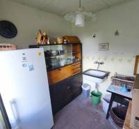 Küche in der Hütte mit Spüle, Kühlschrank, Vitrine und Uhr an der Wand.