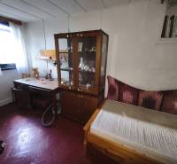 Ein Zimmer mit einem Holzboden, einem Schrank, einem Tisch und einem Bett in einer Hütte.