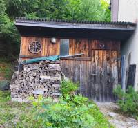Eine Holzhütte im Wald in Kordíky bei Banská Bystrica mit gelagertem Holz.