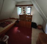 Ein Dachzimmer in einer Hütte mit einem Bett, einem Schrank und einem Boden mit Holzdekor.