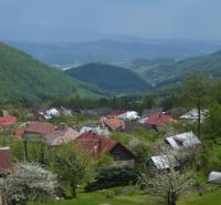 Ein Blick auf die Hütten in Kordíky bei Banská Bystrica mit malerischen Hügeln im Hintergrund.