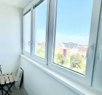 Ein verglaster Balkon mit Blick auf Bratislava, eine Pflanze im Blumentopf, ein Stuhl und ein Tisch.
