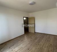 Ein leerer Raum mit Holzboden in einer 3-Zimmer-Wohnung, weiße Wände, offene Türen.
