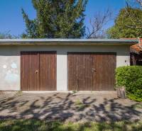 Doppelgarage bei einem Einfamilienhaus in Veľká Paka mit Holztüren und Gartenumgebung.
