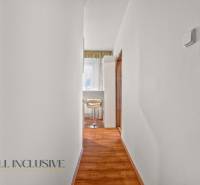 Ein enger Flur in einer 2-Zimmer-Wohnung mit Holzboden und hellen Möbeln.