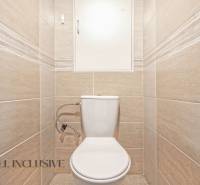 Toilette mit beigefarbenen Fliesen in einer 2-Zimmer-Wohnung.