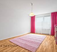 Kinderzimmer in einer Zweizimmerwohnung mit rosa Teppich und Vorhängen.