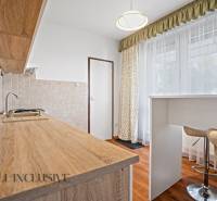 Küche in einer 2-Zimmer-Wohnung mit einer Arbeitsplatte aus Holz und hohen Stühlen.