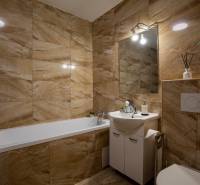 Badezimmer in einem Einfamilienhaus mit Badewanne, Waschbecken und beigefarbenen Fliesen in warmen Tönen.