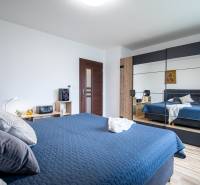 Schlafzimmer mit einem Spiegelschrank in einem Einfamilienhaus, blaue Bettwäsche und Holzdekorationen.