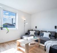 Helles Wohnzimmer in einem Einfamilienhaus mit einem bequemen Sofa, einem Tisch und einem großen Fenster.