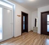 Ein heller Flur mit weißen Wänden, Holztüren und einem Spiegel in einem Einfamilienhaus.