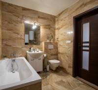 Ein Badezimmer in einem Einfamilienhaus mit Badewanne, Waschbecken und Toilette in warmen Fliesentönen.