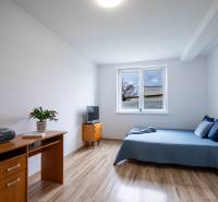 Ein Zimmer in einem Einfamilienhaus mit einem Bett, einem Schreibtisch und einem Fernseher auf einem hellen Boden.