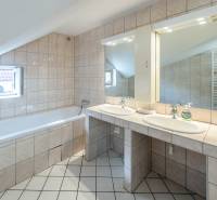 Das Badezimmer im Einfamilienhaus hat eine Badewanne, ein Doppelwaschbecken und beleuchtete Spiegel.