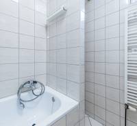 Ein Badezimmer in einem Einfamilienhaus mit weißen Fliesen und einer Badewanne.