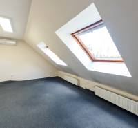 Dachzimmer mit Teppich, Dachfenstern, Klimaanlage und Heizkörper in einem Einfamilienhaus.