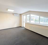 Ein heller Raum in einem Einfamilienhaus mit Teppichboden und Klimaanlage, große Fenster mit Jalousien.