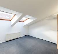 Ein Dachzimmer in einem Einfamilienhaus mit zwei Dachfenstern und einer Holztür.