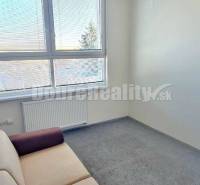 Büros mit einem Sofa und einem großen Fenster, Teppichboden und weißen Wänden, ideal zum Arbeiten.