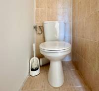 Toilette mit weißer Schüssel und Fliesen in einer 3-Zimmer-Wohnung.