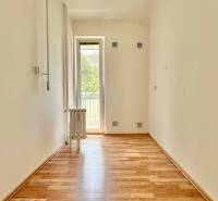 Ein Zimmer mit Holzboden und Balkon in einer 3-Zimmer-Wohnung, weiße Wand, Heizkörper.
